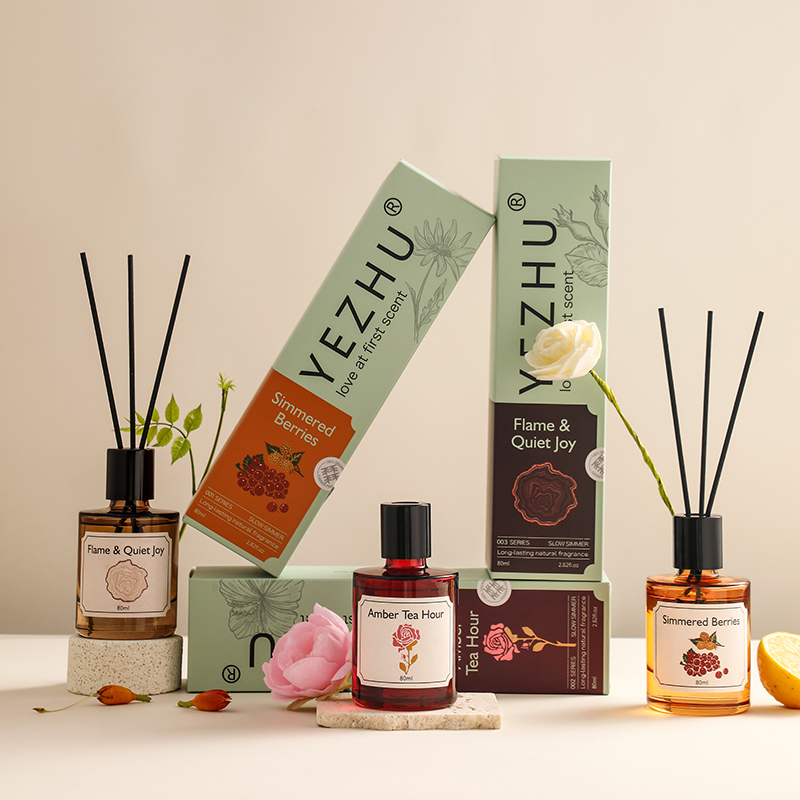 Three reed diffuser bottles with black closures, reeds, printed labels and matching retail boxes